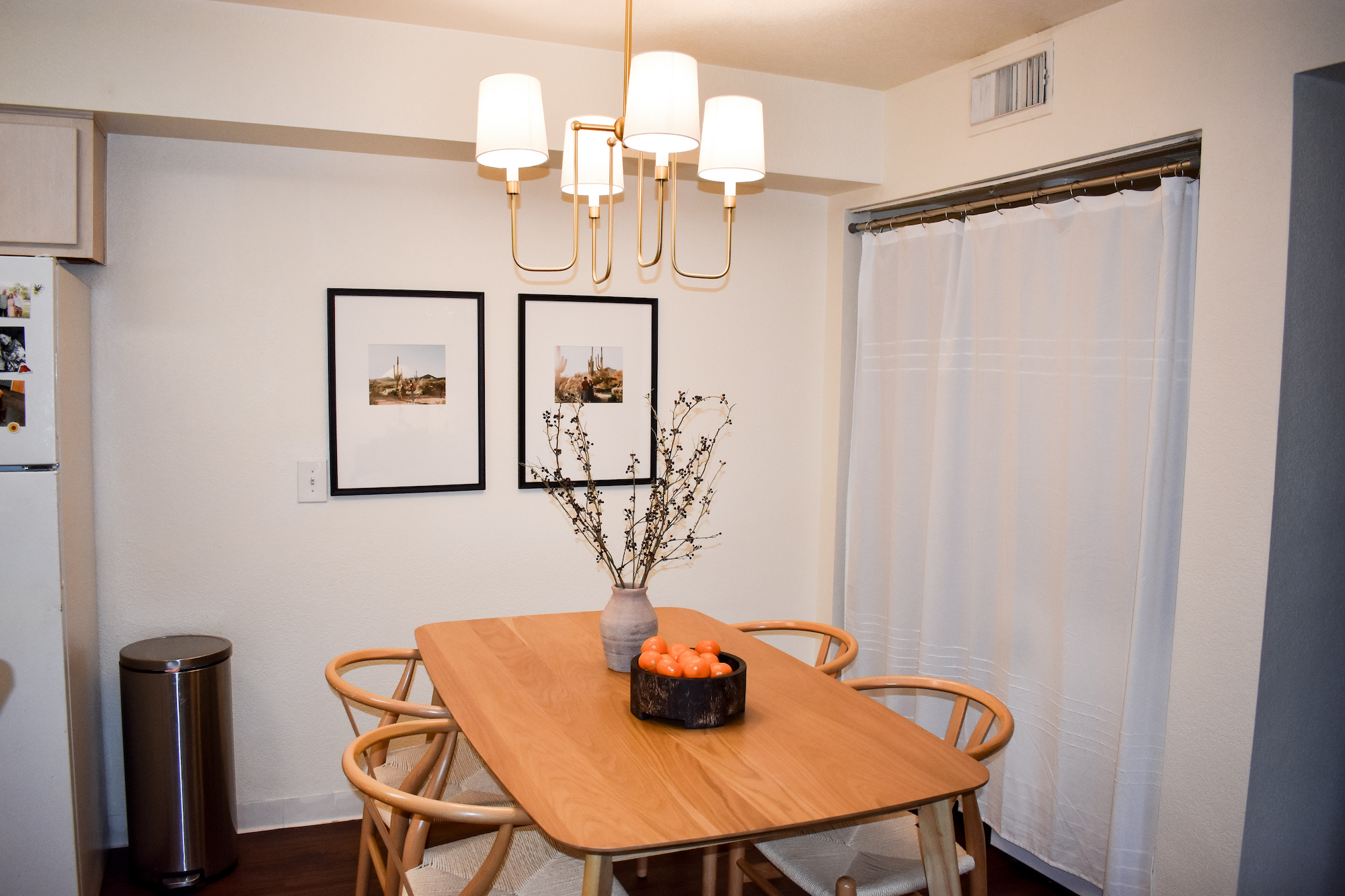 Dining area setup with dining set and chairs with modern light and frames hanging on wall