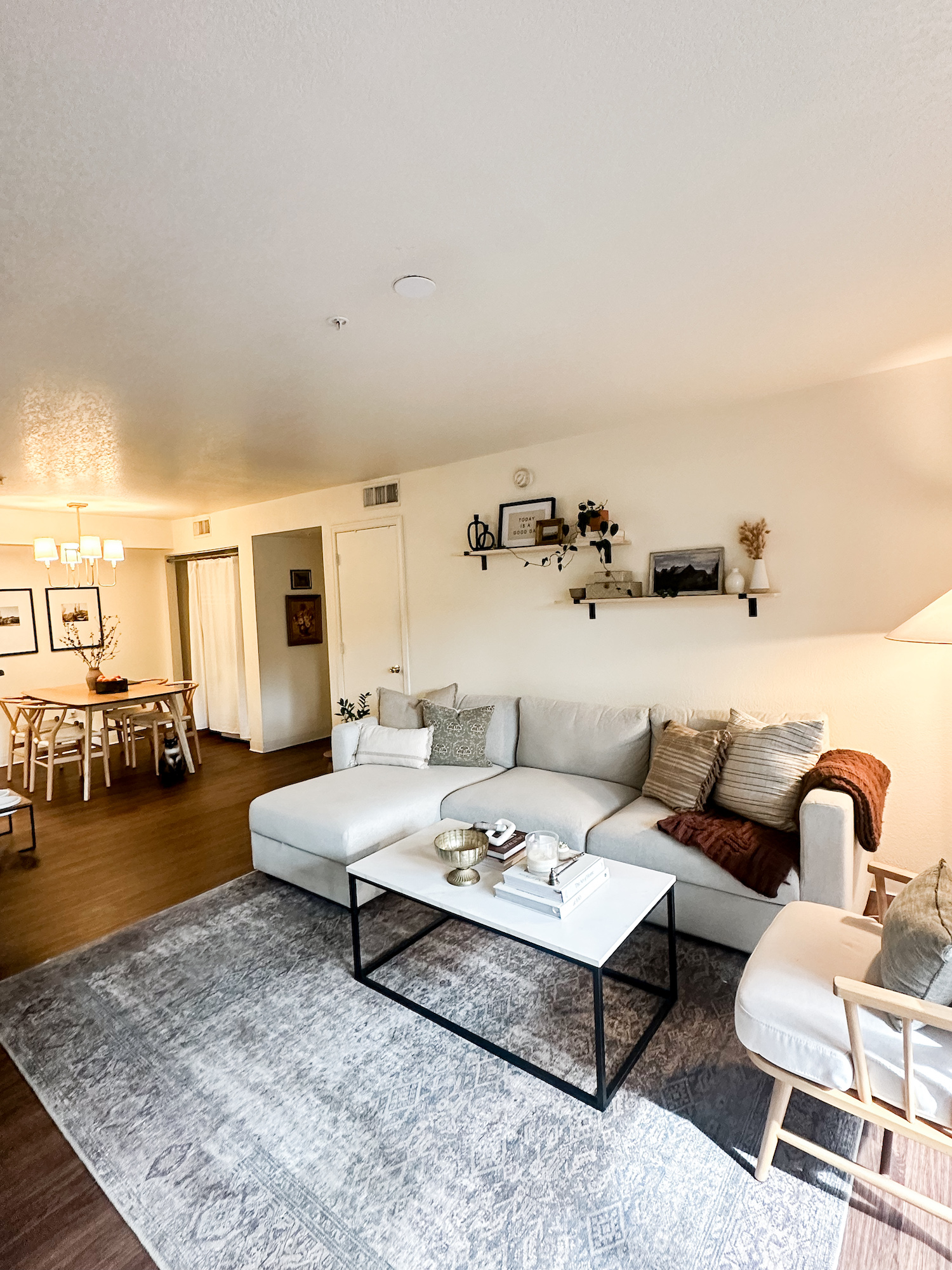 View from living room showing couch setup with dining room and hallway in background